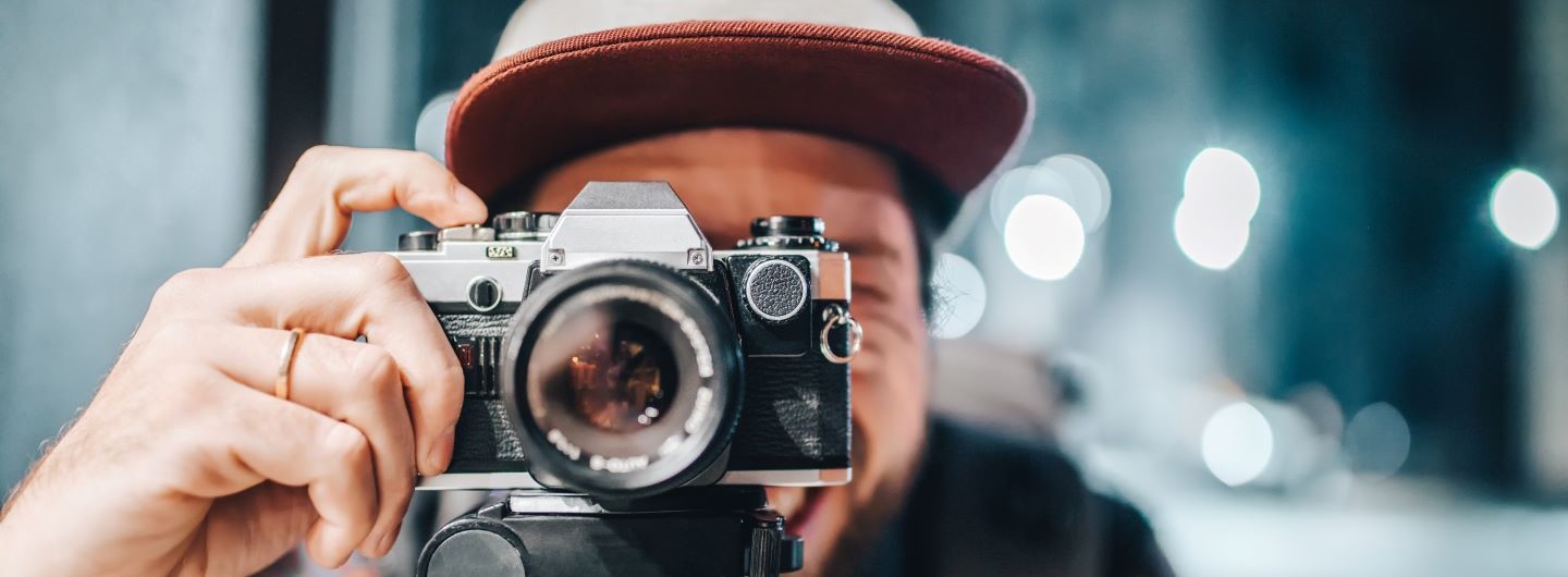 Fotografie Studium: Mann fotografiert mit analoger Kamera
