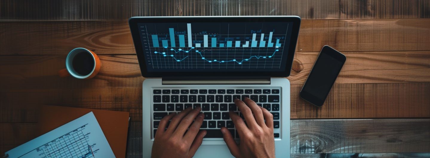 Ökonom Weiterbildung: ein Ökonom tippt auf seinem Laptop mit Statistiken auf dem Monitor