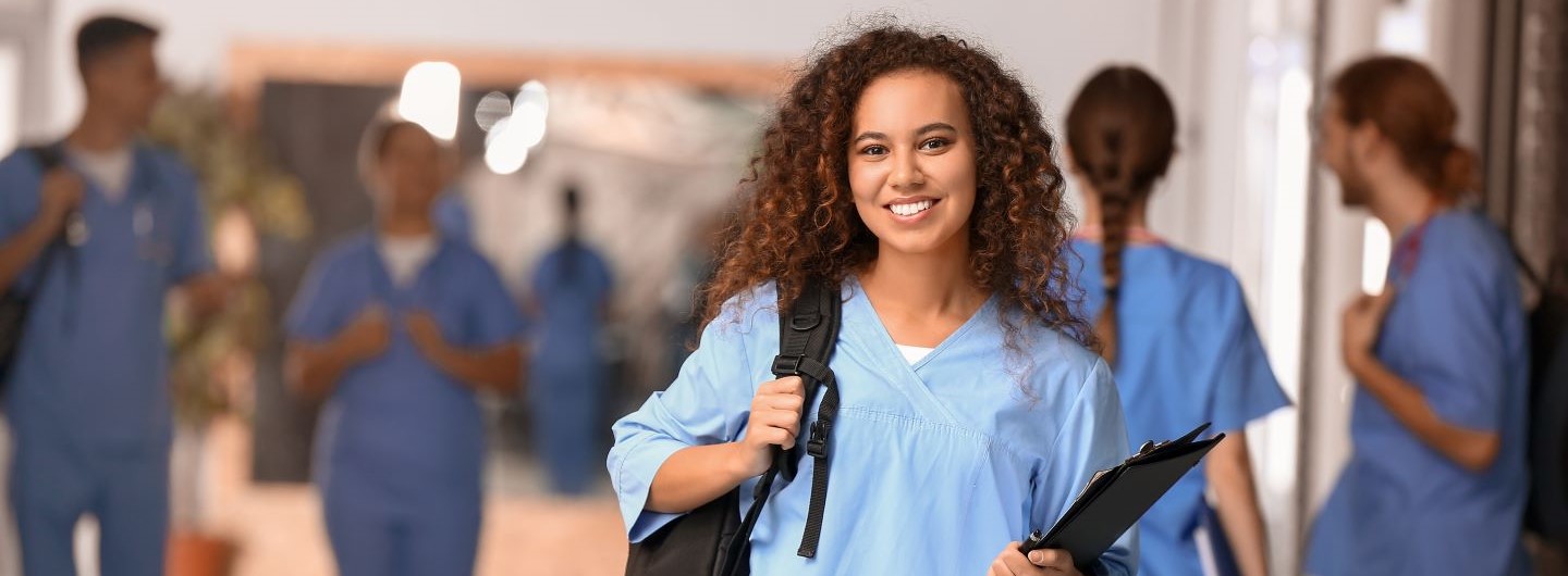 Eine hübsche Medizinstudentin hält ein Klemmbrett in der Hand und lächelt in die Kamera